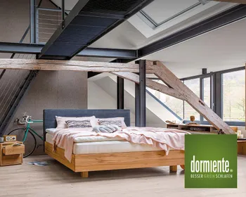 Bett mit Holzgestell im hellen Schlafzimmer mit Dachschrägen und schlafendes Kind auf dormiente-Kissen